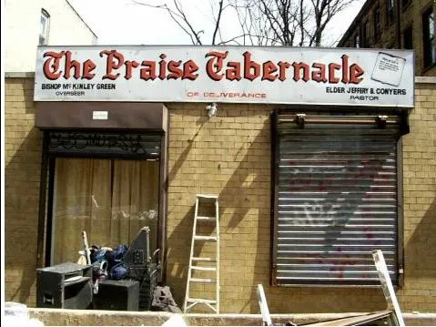 Run-down storefront with peeling signage and shuttered doors.