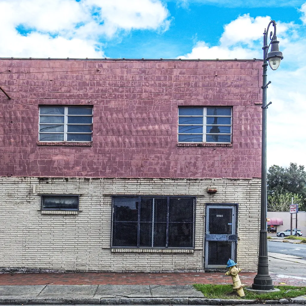 Weathered building with peeling paint and small windows.