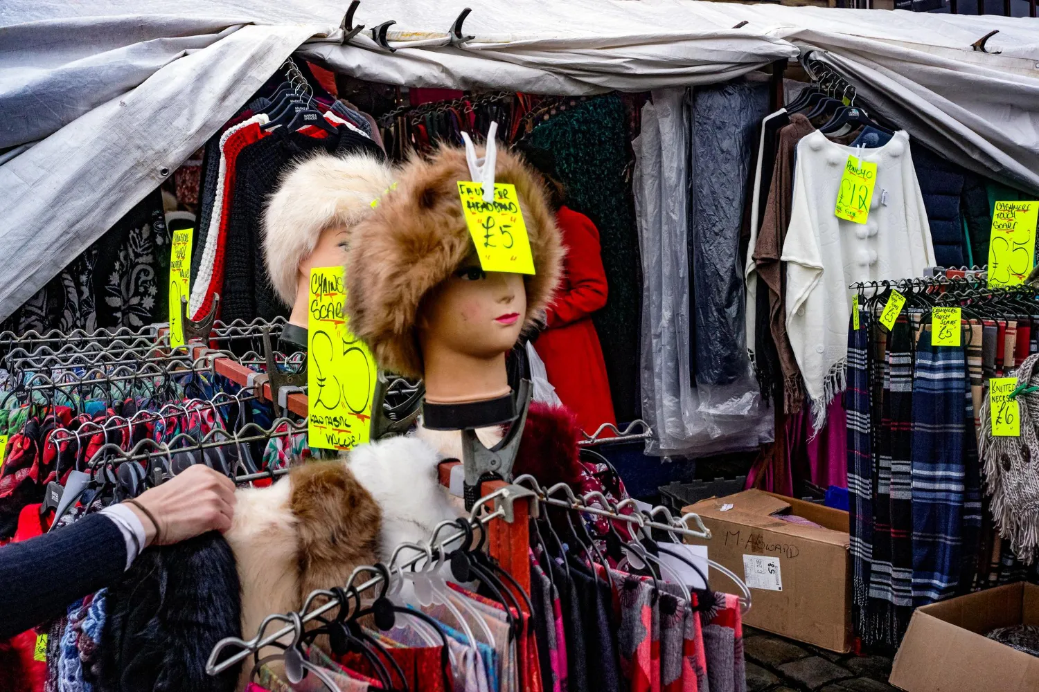 Market stall crowded with mismatched goods and neon price tags.